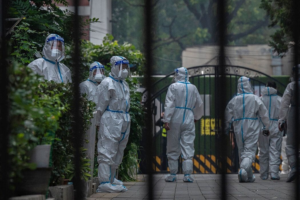 上个月，在北京发现新冠病例后，卫生和安全人员进入了一个被封锁的大院。