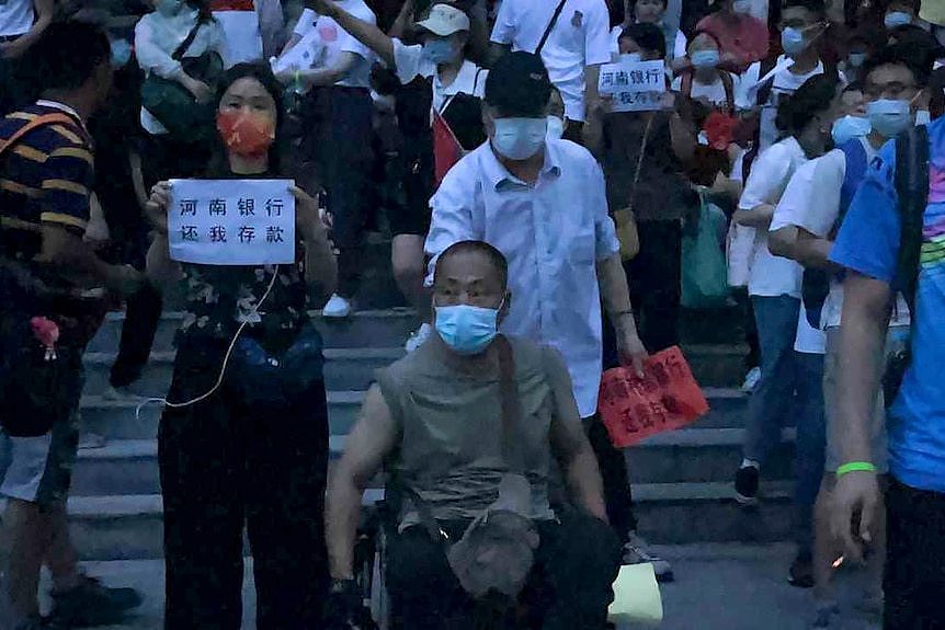 在中国中部河南省郑州市的中国人民银行分行，人们举着横幅举行抗议活动