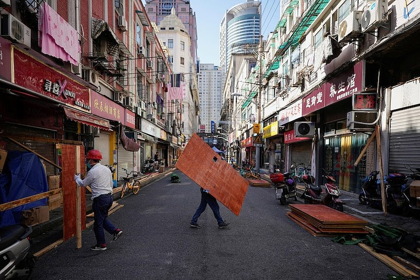 戴着安全帽的工人正在拆除上海大街上商店周围的栅栏