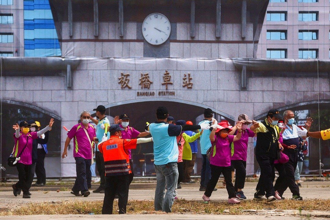 台湾新北市本月14日举行“民安”演习模拟中国攻台，警察和消防员帮助人们从为配合演习所搭建的假火车站撤离。（图取自路透社）
