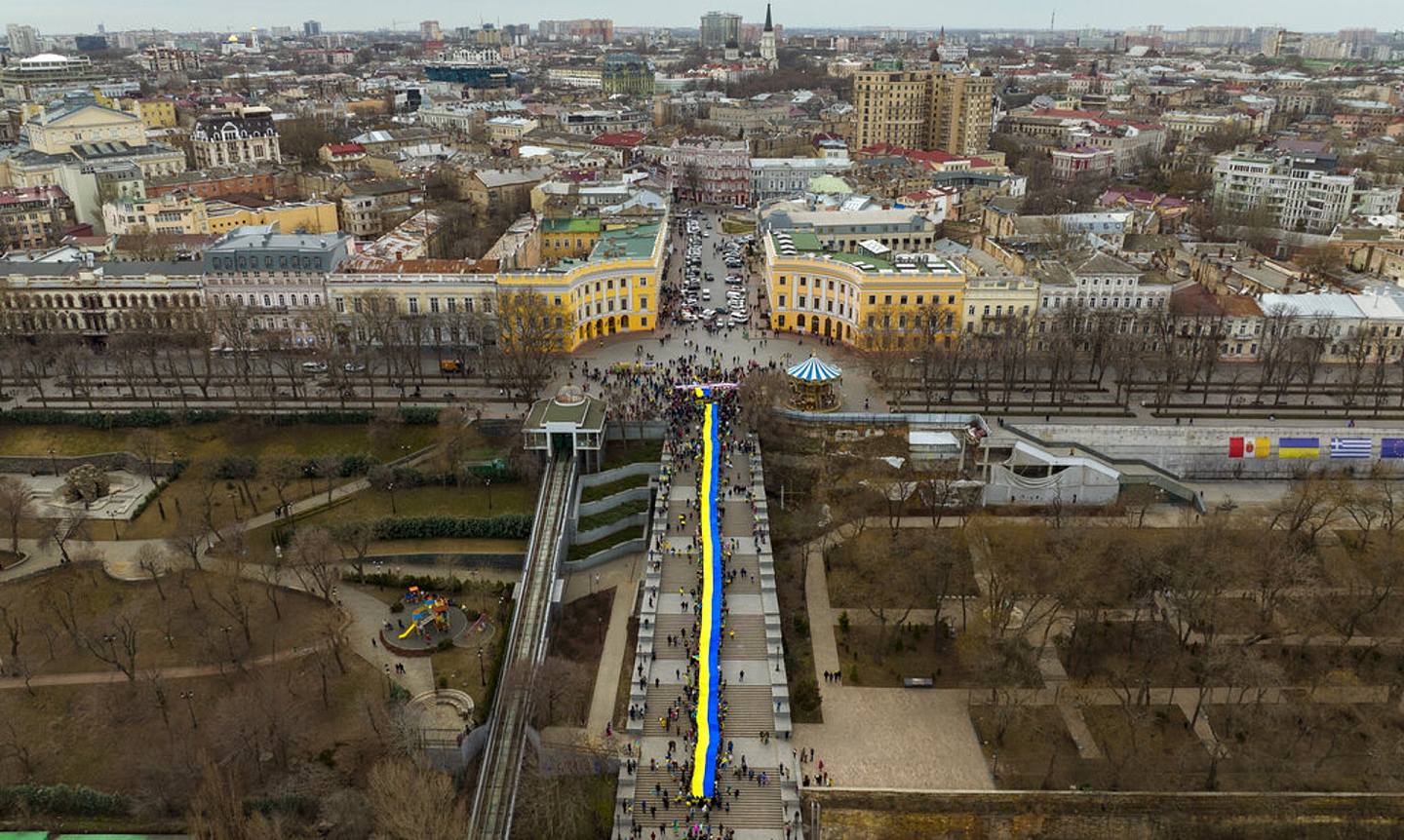 乌克兰局势：俄罗斯2月24日挥军乌克兰后，乌克兰的港口出口瘫痪，其中一个深受影响的就是敖德萨。 图为2022年2月20日，示威者在乌克兰敖德萨的街道上举起一面巨大的乌克兰国旗游行。 （AP）