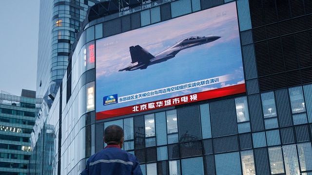 Man at shopping centre in Beijing watches a news broadcast showing a fighter jet during Chinese military operations near Taiwan, 3 August 2022