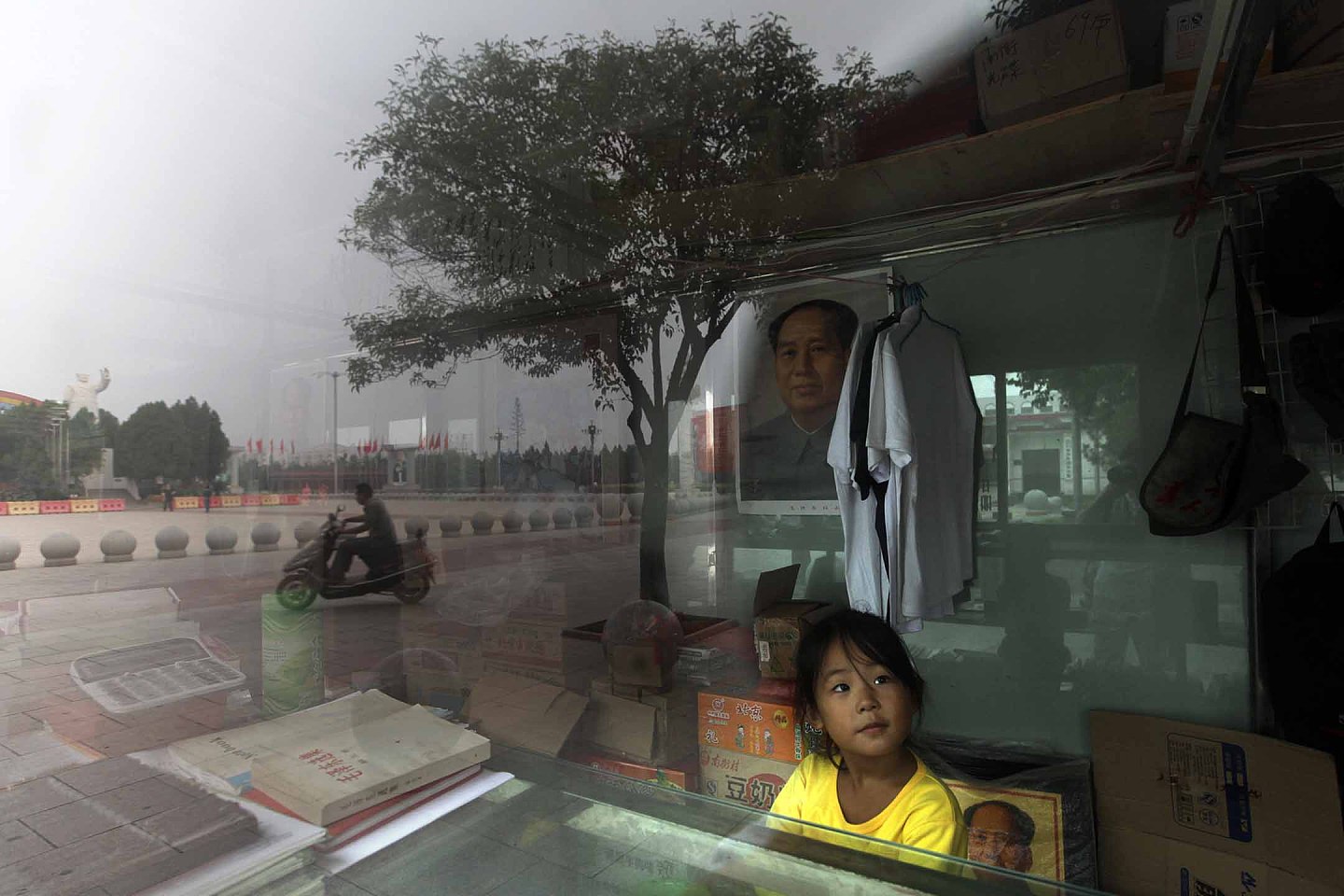 2012年9月24日，河南省漯河市的一家纪念品商店，一个女孩在毛泽东的肖像旁。