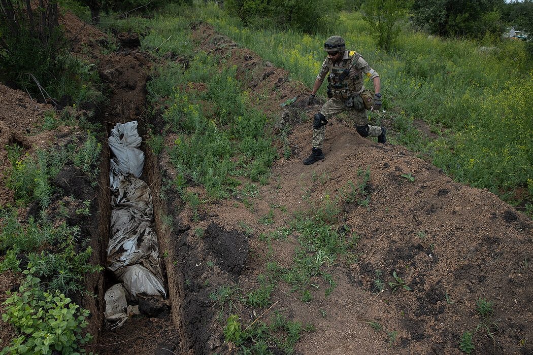 6月中旬在利西昌斯克一处乱葬岗旁的乌克兰士兵，这里埋葬了数百具无人认领的平民尸体。这些只是因为“没人把他们葬在花园或后院”，一名士兵平淡地说。