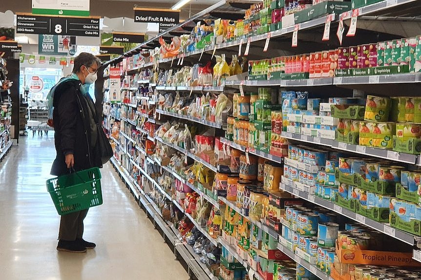 Woman in mask shopping in Woolworths packaged food aisle June 28