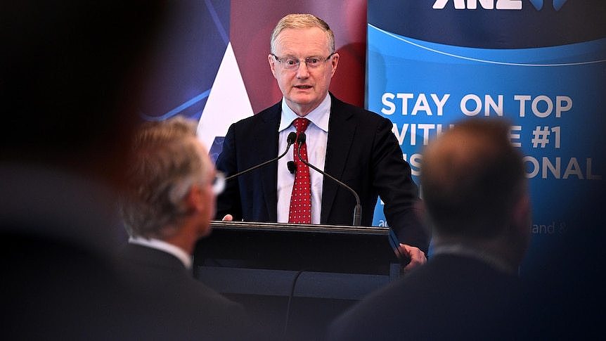 A man in a suit stands behind a podium. 