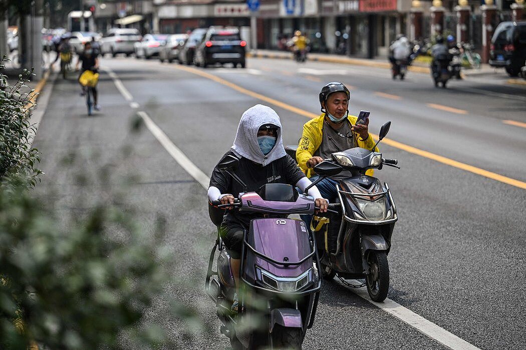 上海的一名女子把毛巾包在头上防晒，摄于上周。中国多地正在遭遇创历史新高的高温天气。