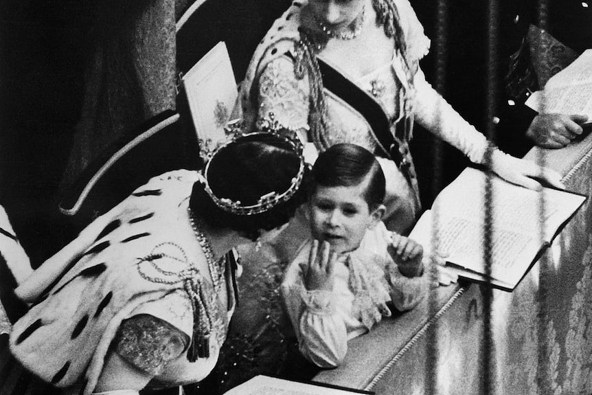 A black and white photo of four-year-old Charles with the Queen Mother and Princess Margaret at his mother's coronation.