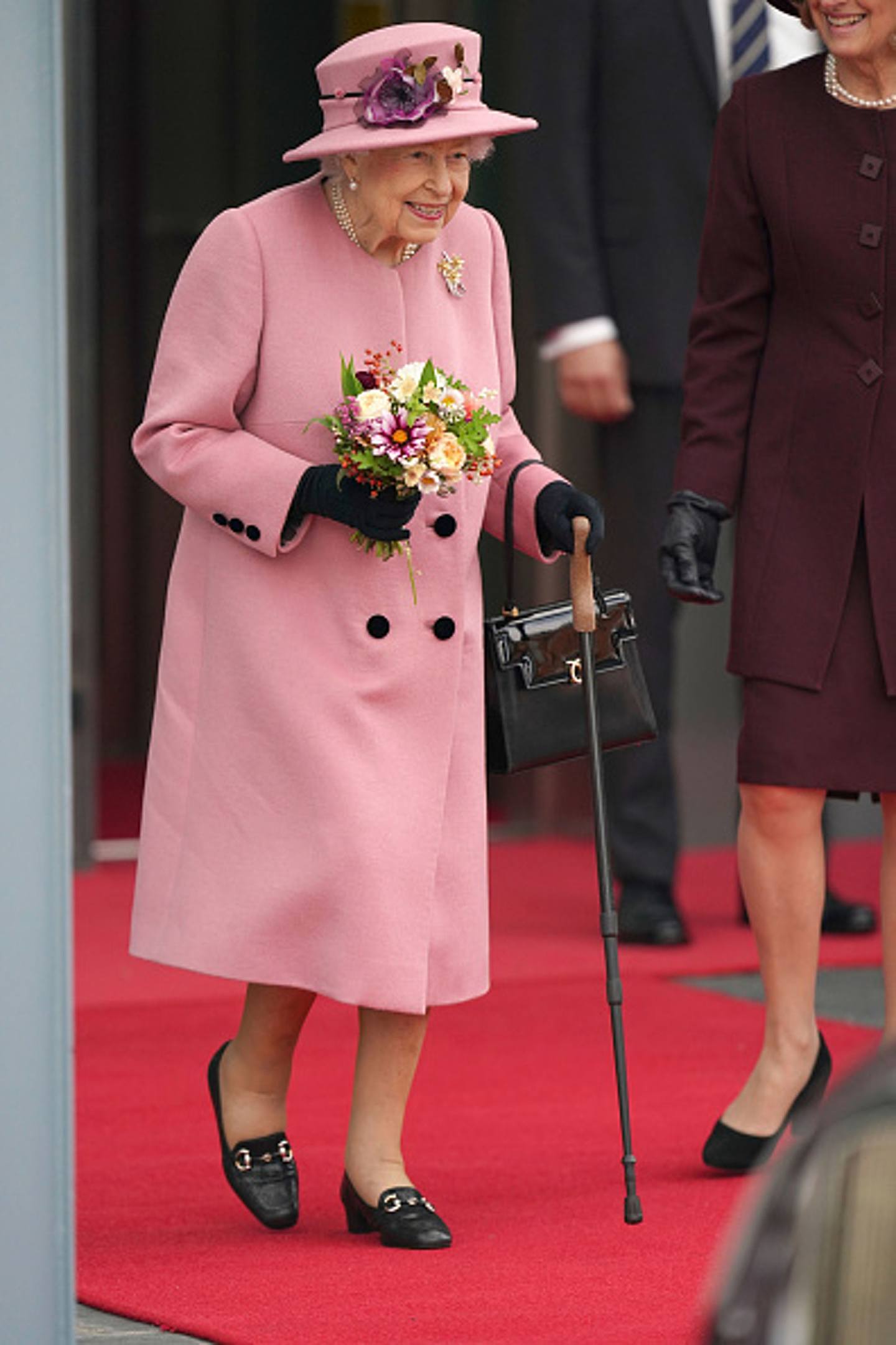 英女王伊利沙伯二世：一生受尽尊荣爱戴的同时，英女王亦分秒活在公众眼前，受大堆繁文缛制约必须规行距步，不能行差踏错，跟溥仪和父王乔治六世同样命运不可自决。 图为英女王2021年10月14日在卡迪夫出席威尔斯议会开幕仪式时的情形。 她被拍得步行时需用手杖，但其健康状况基本上是良好的。 （Getty）