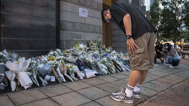英国驻香港总领事馆外一位男士向市民留下悼念英女王伊丽莎白二世的花堆鞠躬（9/9/2022）