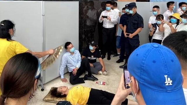 2021年9月，恒大总部门前，一位高管瘫坐门前，面对抗议者此起彼伏的“还钱”呼声——成为这个中国最大房企陷入危机的经典一幕。
