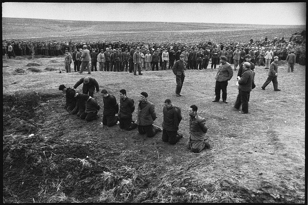 在这张由李振盛拍摄的照片中，八名被指控为罪犯和反革命分子的人在处决前双膝跪地。