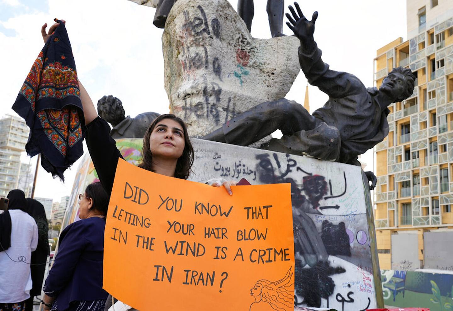 9月21日，黎巴嫩貝魯特市中心的烈士廣場，一名敘利亞婦女手持頭巾和標語牌，抗議伊朗少女阿米尼離奇死亡案。（AP）