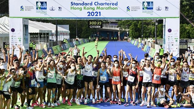 香港维多利亚公园内群众跑手们在渣打香港马拉松冲线处合影留念（中新社图片24/10/2021）
