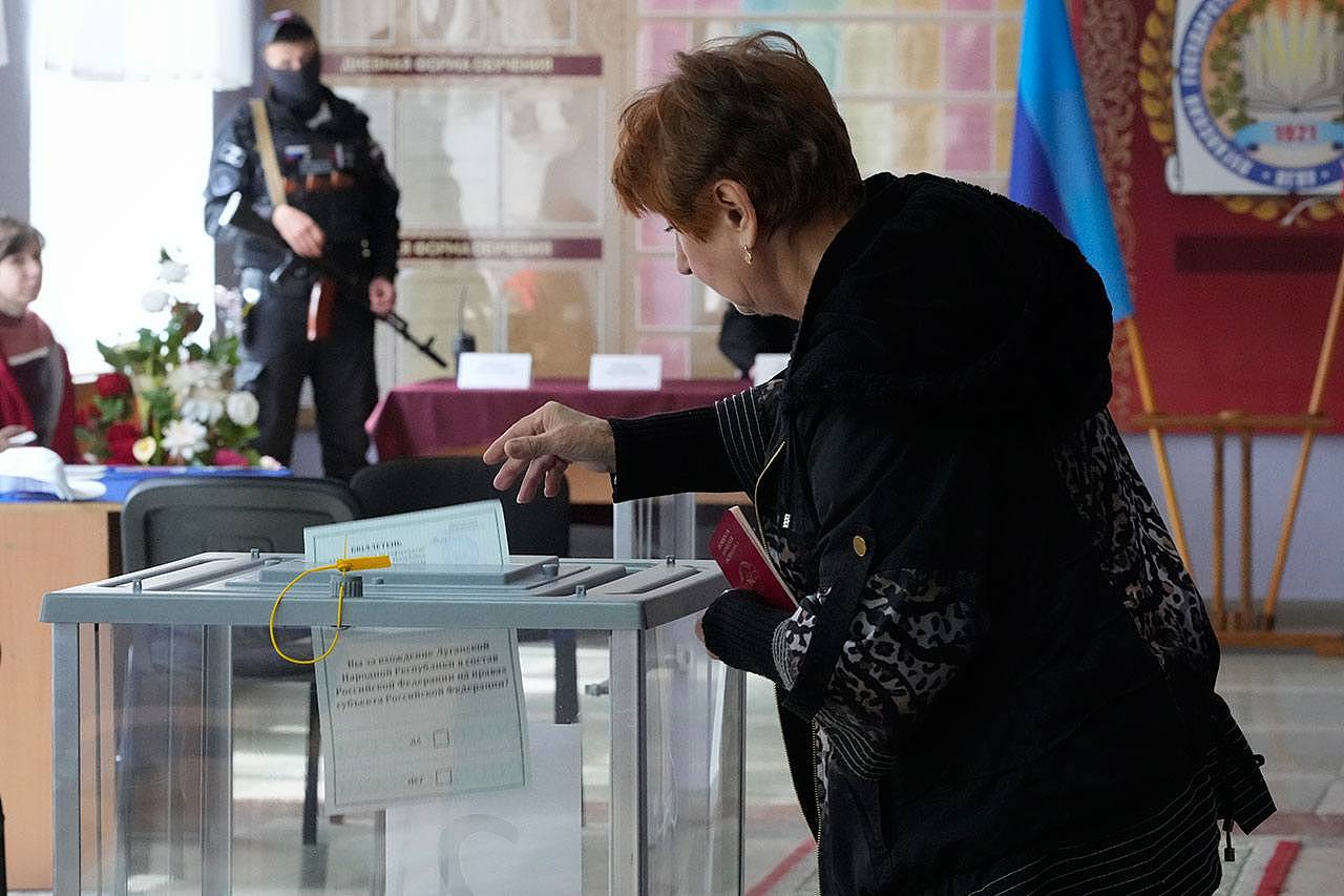 在乌克兰卢甘斯克，1名妇女在俄罗斯士兵的注视下公投。（美联社）