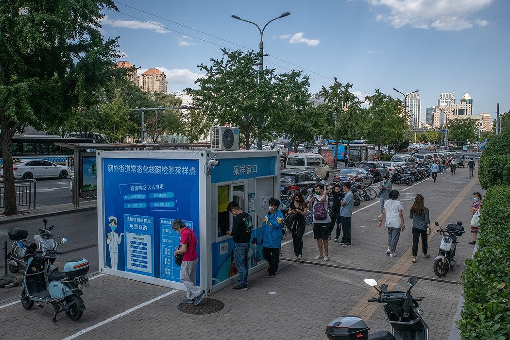 人们在北京的一个核酸检测点排队检测。 北京经常在国家电视台上宣传其新冠核心政策，包括封锁、大规模检测和密接追踪。