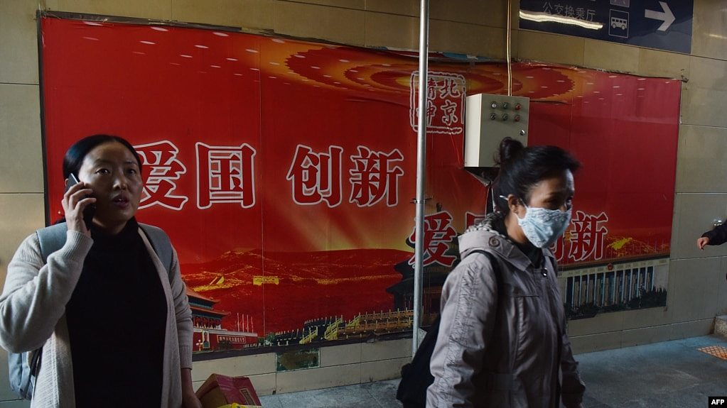 人们走过北京地铁站入口处的“爱国，创新”宣传广告牌（2018年10月19日）。