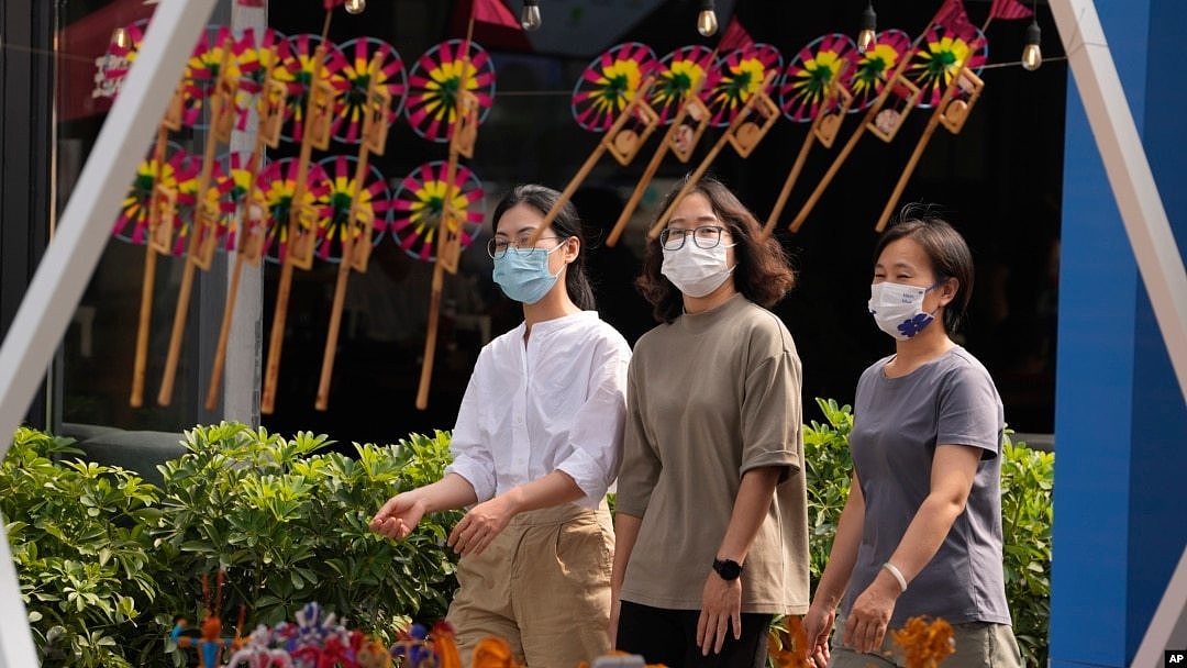 戴着口罩的行人走过北京街头一个售卖传统风车玩具的商铺。（2022年9月13日）