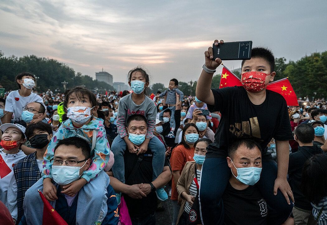 10月1日，在北京天安门广场附近观看国庆节升旗仪式的民众。 新冠病毒感染人数近期激增的部分原因是为期一周的国庆假期。