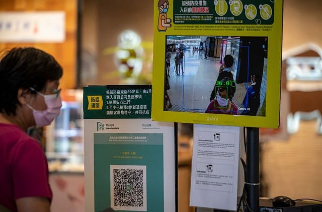 香港一家购物中心内的商店入口处放置了“安心出行”二维码和温度检测点。