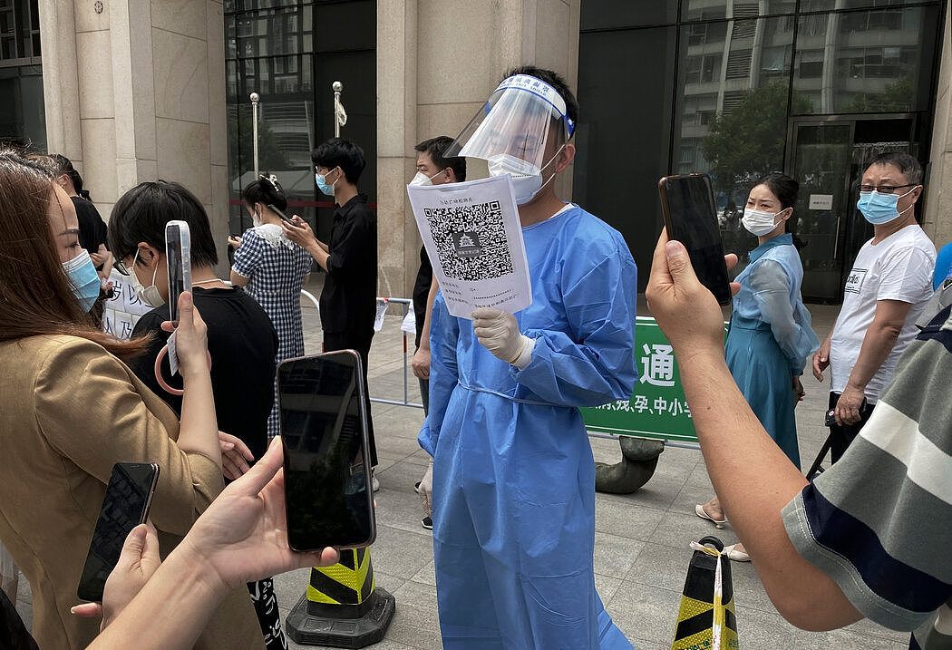 在北京CBD，人们扫描健康码，排队接受新冠病毒检测。 每个公共空间的入口处都有一个打印出来的二维码，人们必须用手机扫描二维码来打卡。