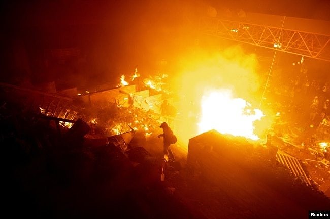 香港理工大学的抗议者站在燃烧的大火旁。（2019年11月18日）