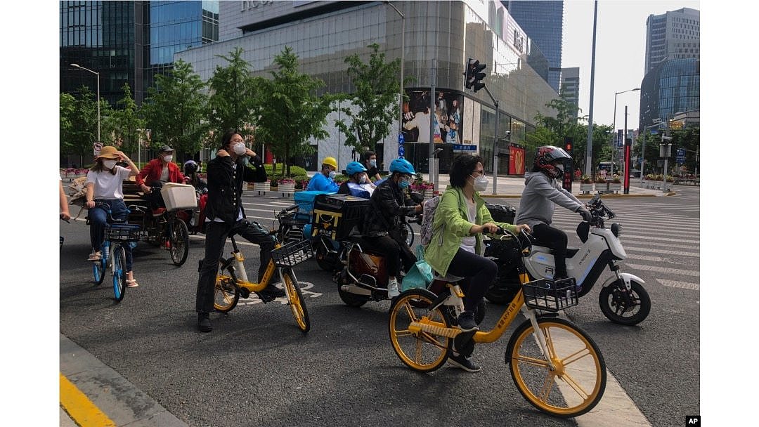 上海市民和快遞小哥騎著車在街頭等交通燈。（2022年5月31日）