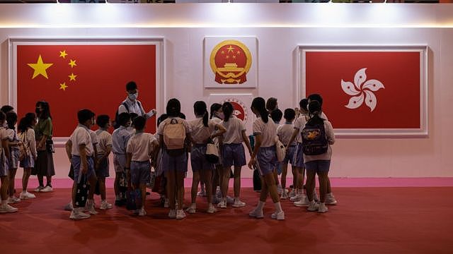 一群小学生在香港特区成立25周年展览上观看有关中国国旗与香港区旗的展板（2/9/2022）
