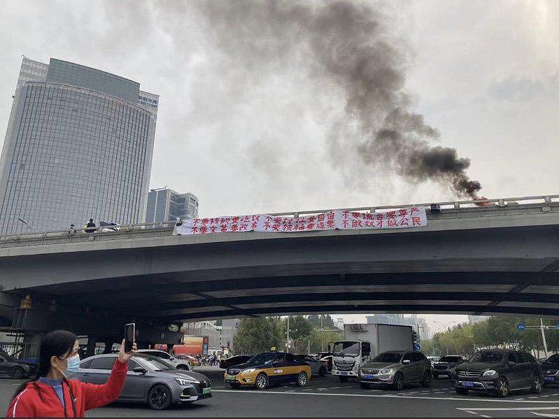 北京一名男子在桥上悬挂反习近平布条，当场被警方逮捕，现场还冒出黑烟。 (取自推特)