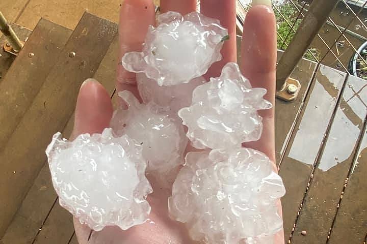 A hand holding five hail stones