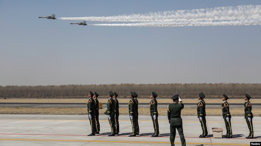 中国士兵们站立在辽宁沈阳一个机场上，空军两架歼-11战机飞越上空。 （2019年4月3日）