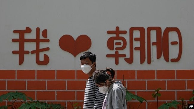 北京朝阳区两个带着口罩的居民去排队做新冠核酸检测。（2022年5月11日）