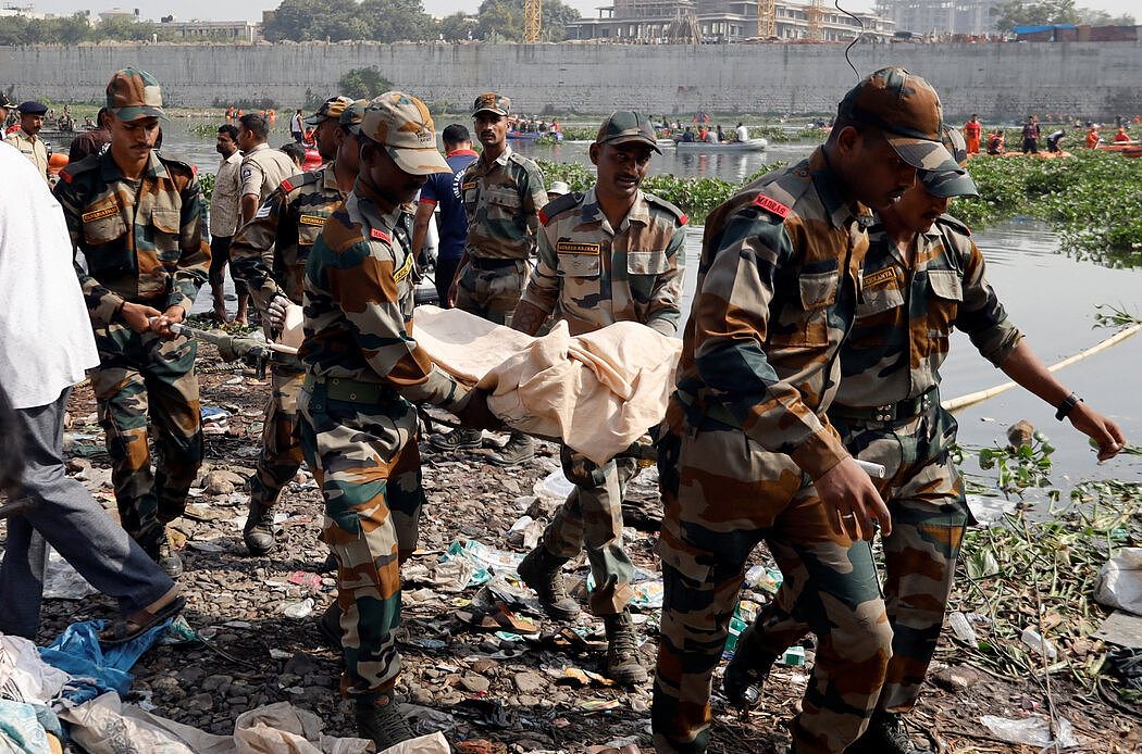 周一，莫尔比的军人抬着遇难者的尸体。过度拥挤导致的基础设施故障在印度很常见。