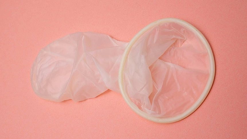 没有包装的避孕套放在粉红色的背景上