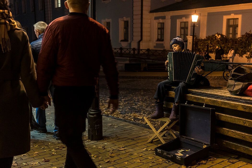 周六天黑后，一个男孩在安德烈斜坡为路人演奏手风琴。