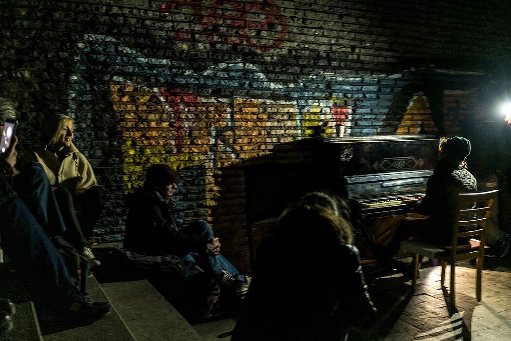 音乐家米莎·卡丘在地下通道中为一小群人弹奏钢琴和唱歌。