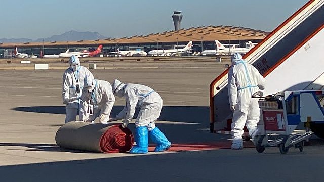 Workers in protective suits roll out a carpet near an airplane carrying German Chancellor Olaf Scholz as he arrives for a visit in China, at the Beijing Capital International Airport, in Beijing, China November 4, 2022