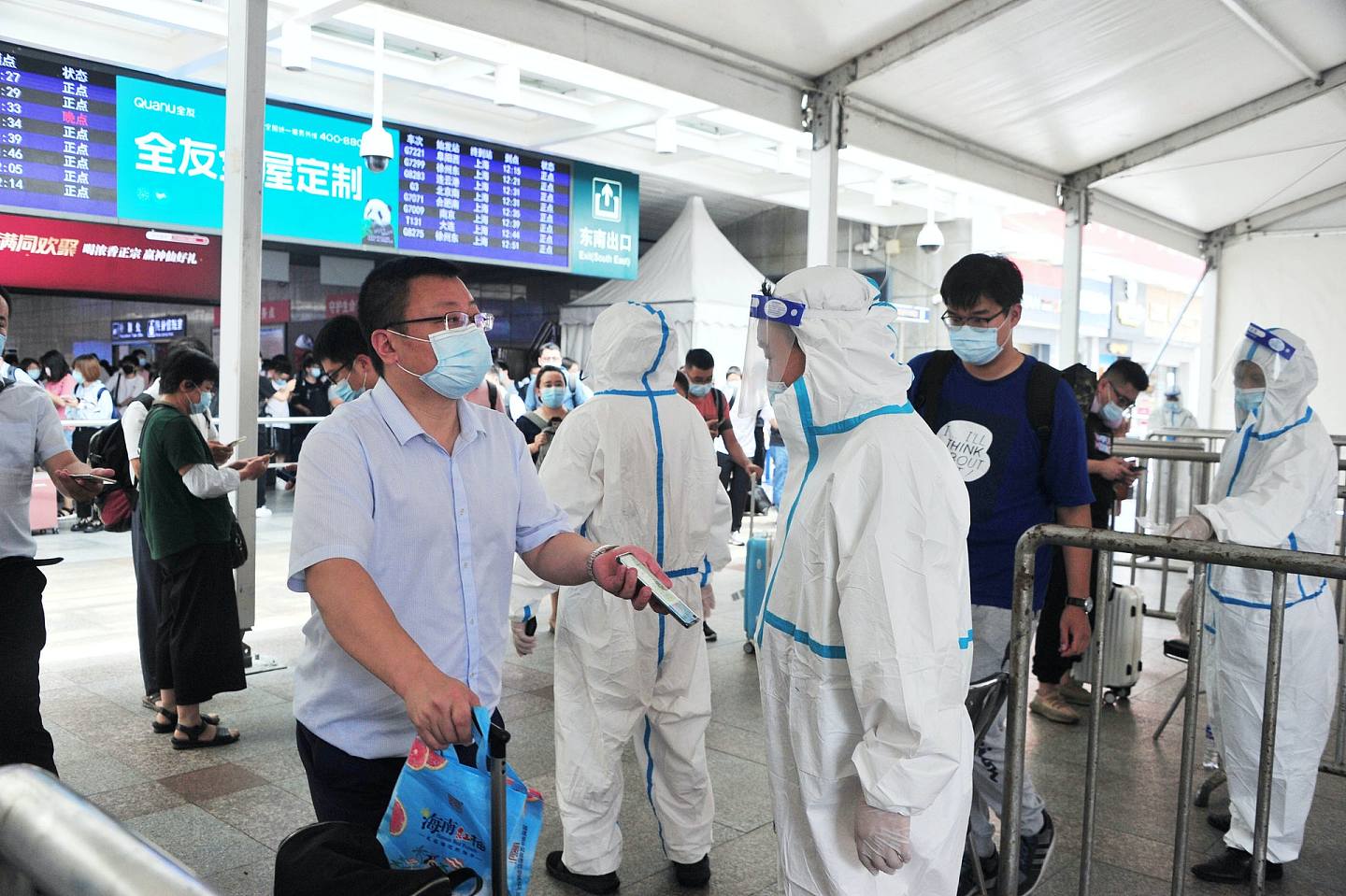 穿着白色防護服的工作人員逐個檢查旅客的健康碼。（人民視覺）