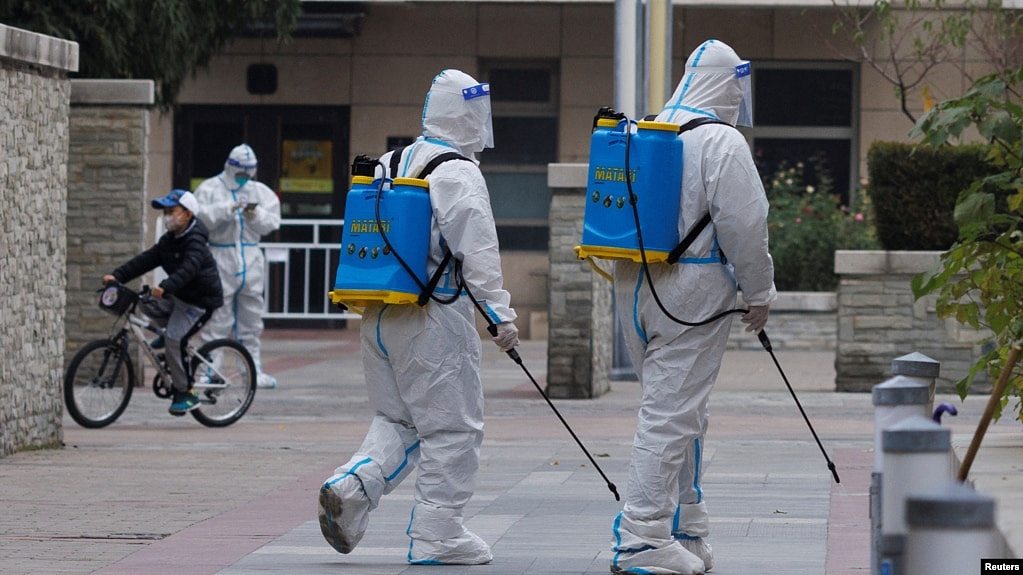 身穿防护服的防疫人员在北京一个被封的居民区喷洒消毒药水。（2022年11月9日）