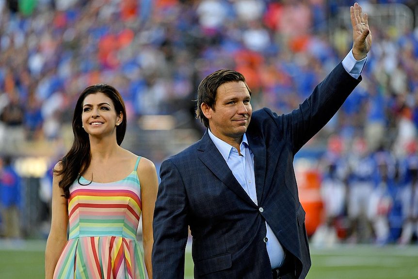 Ron DeSantis and his wife smiling and waving 