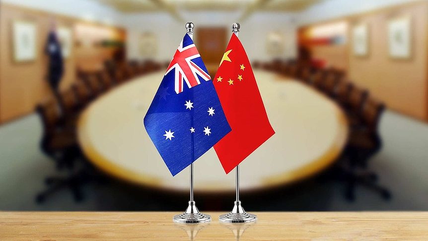 Australian and Chinese flags in the foreground with a board room table in the background.