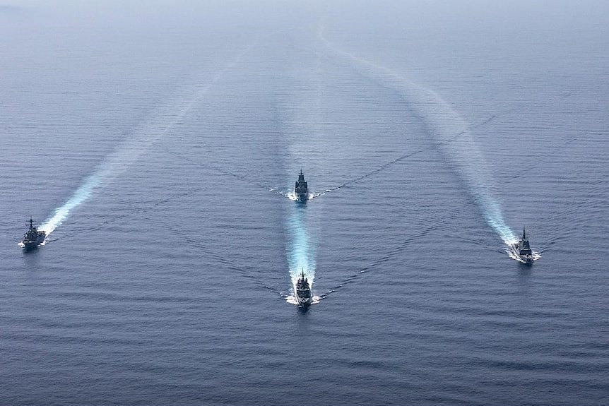 Four navy ships sailing in formation