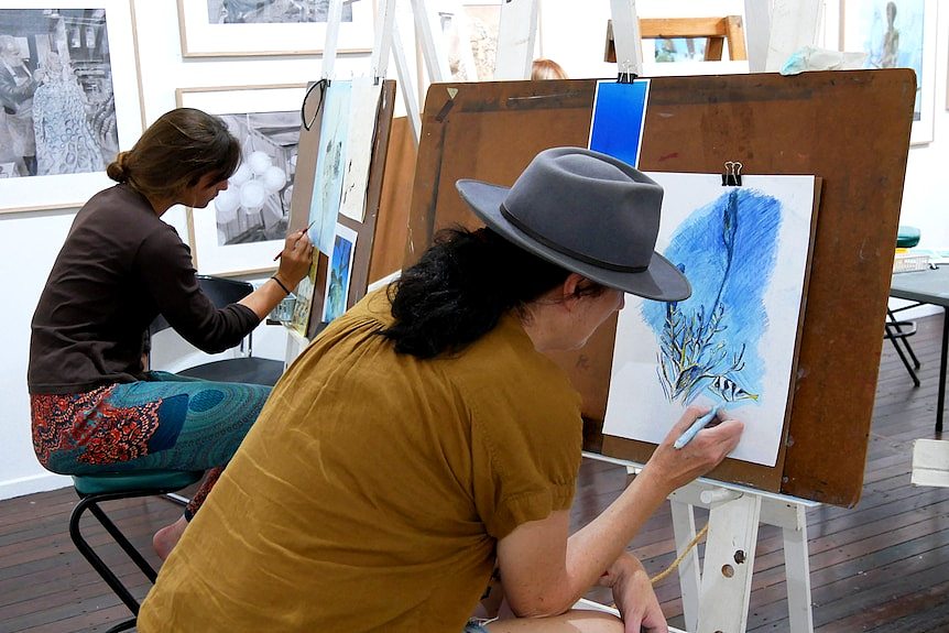 Two woman work on drawings in an art studio
