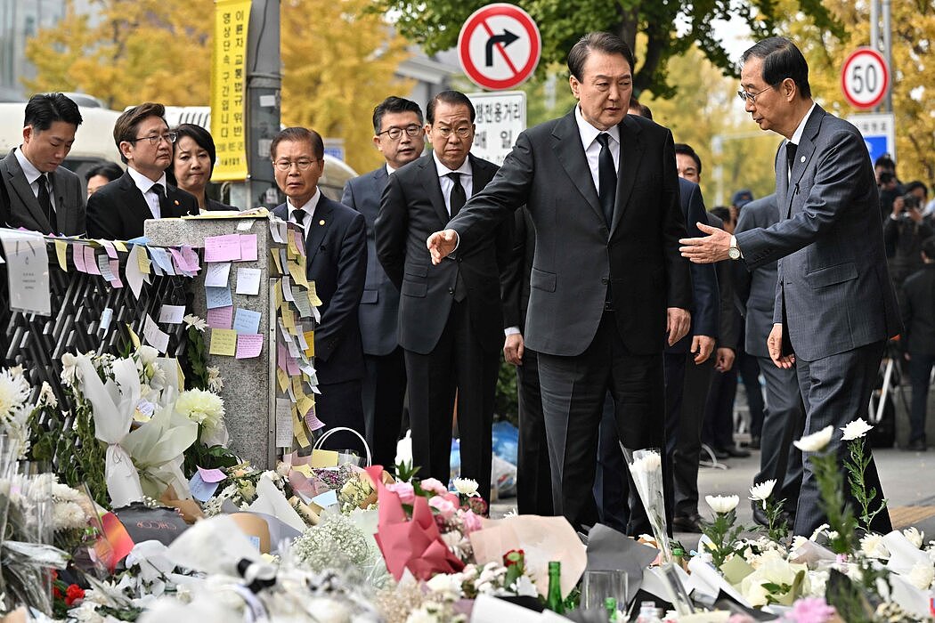 韩国总统尹锡悦（中）和韩国总理韩德洙（右）在梨泰院地铁站外的非正式纪念仪式上。 梨泰院地铁站就在事故发生地附近。