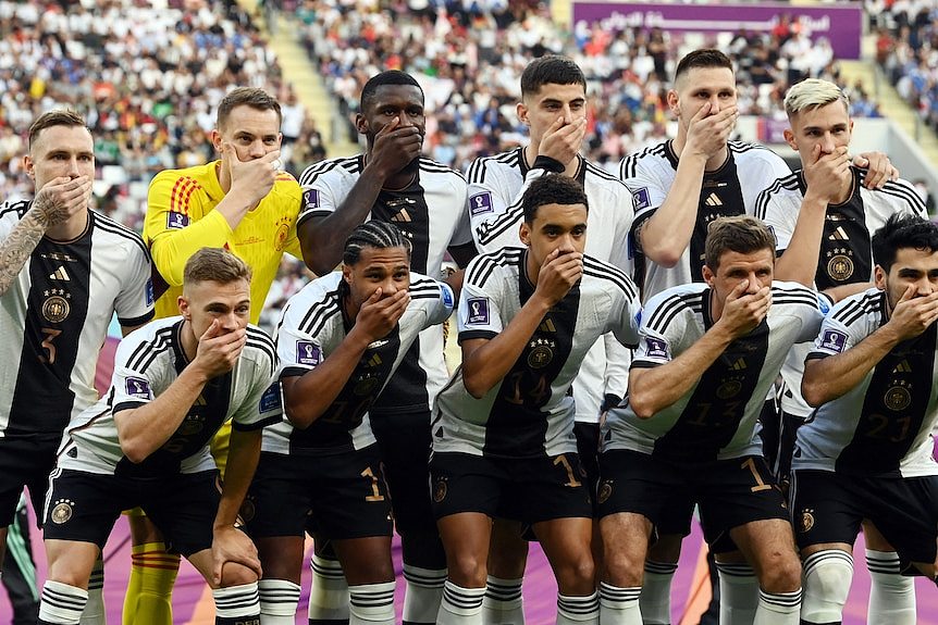 Players pose together with one hand over their mouths, 