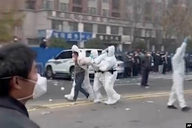 中国河南郑州富士康代工厂里身穿防护服的警察和保安殴打并逮捕参加示威活动的工人。(2022年11月23日)