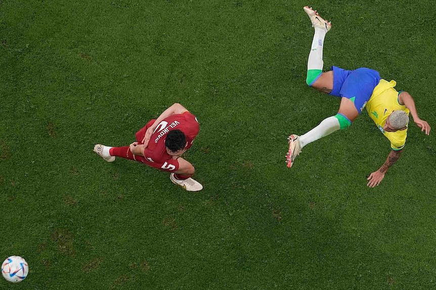 Richarlison kicks a ball past a Serbian defender at the Qatar World Cup.