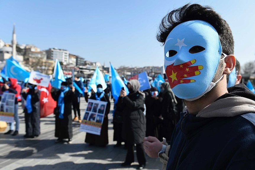 A man wearing a mask with the East Turkistan and Chinese flags