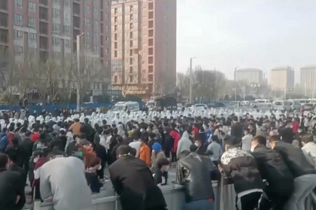视频截图显示，富士康在郑州运营的一个厂区内，抗议者与身穿白色防护服的保安人员发生了冲突。