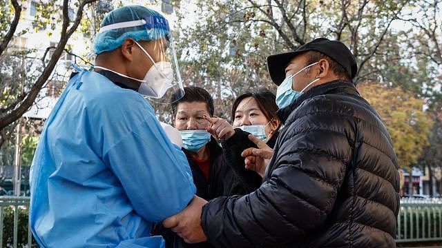 11月21日，一名妇女（右二) 在北京某处新冠测试点与一名志愿卫生工作者（左）争论